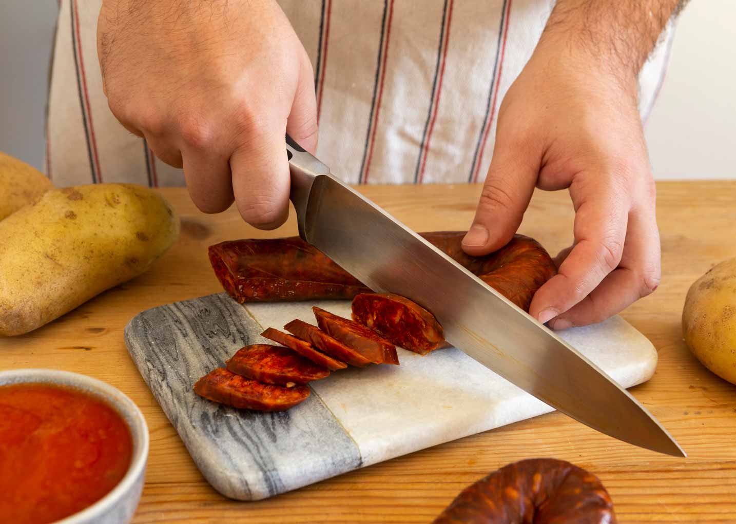 Detalle de hombre cortando a cuchillo chorizo ibérico
